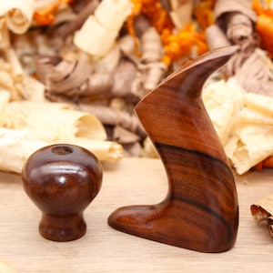 May include: Two wooden handles for a woodworking tool. The handles are made of dark brown wood with a grain pattern. One handle is a knob shape and the other is a long, curved handle.