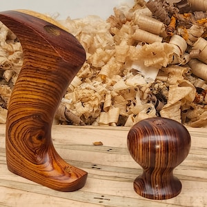 May include: Two wooden handles for a hand plane, one is a full handle and the other is a knob. Both are made of dark brown wood with a grain pattern.