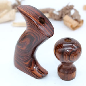 May include: A set of two wooden hand plane handles. The handles are made of dark wood with a reddish brown color and a grain pattern. The handles are designed for a hand plane.