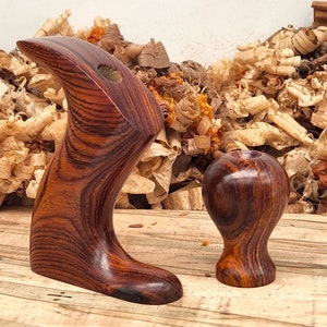 May include: Close-up of a wooden hand plane handle and knob. The handle is a dark reddish-brown with a striped pattern. The knob is a similar color and has a rounded shape.