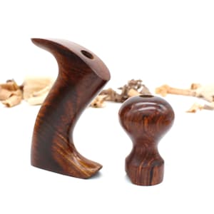 May include: Two wooden hand plane handles, one with a curved shape and the other a round knob. Both are made of dark wood with a reddish brown hue.