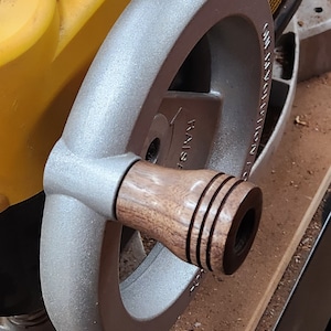 May include: A silver metal hand wheel with a wooden knob. The knob has three grooves and the wheel has the text "RAISE" and "INSPECTION 1000" on it.
