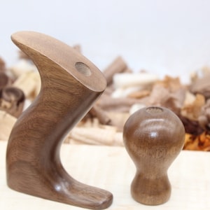 May include: Two wooden hand planes with a dark brown finish. The larger plane has a curved handle and a hole in the top. The smaller plane is round with a hole in the top.
