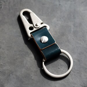 May include: A dark blue leather key chain with a silver metal hook and a silver ring.