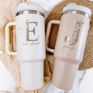 May include: Two personalized stainless steel travel mugs with floral designs and initials. The white mug says "mrs. elliott" and the pink mug says "jennifer".