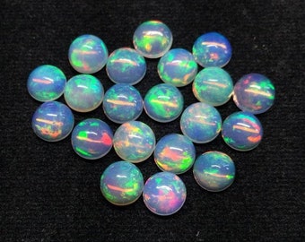 May include: A collection of round, iridescent opal gemstones. The opals display a play of color with flashes of blue, green, and red. The gemstones are set against a dark background, highlighting their vibrant hues.