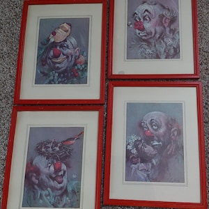 May include: Four framed vintage clown prints with red frames. Each print features a different clown portrait with a red nose and expressive face. The clowns are surrounded by various floral and natural elements.