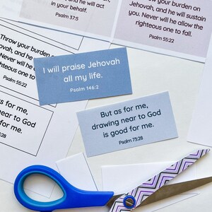 Op de afbeelding: Een set blauwe en witte kaarten met inspirerende citaten uit de Bijbel. De kaarten bevatten verzen uit Psalm 37:5, 55:22, 146:2 en 73:28. De kaarten liggen op een wit oppervlak met een schaar.
