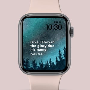 Op de afbeelding: Een zilveren smartwatch met een lichtroze band toont een blauwgroen scherm met de tekst "Give Jehovah the glory due his name. Psalm 96:8." De tijd is 10:30 uur op vrijdag 11 november.