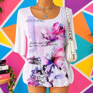 Könnte beinhalten: Ein weißes Oberteil mit Dreiviertelarm und einem Aquarell-Druck aus rosa und violetten Blumen sowie einem Schmetterling. Der Text "I am not Perfect I am Just a Limited Edition" ist auf der Vorderseite aufgedruckt. Eine weiße Umhängetasche wird getragen.