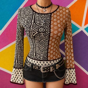 Peut inclure: Un haut à manches longues présentant un design divisé avec un motif cachemire complexe noir et blanc d'un côté et un imprimé floral marron et blanc de l'autre. Le vêtement est associé à une mini-jupe en jean noir avec une ceinture à clous.