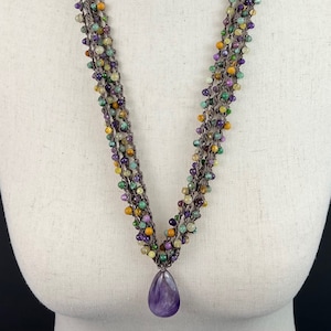 May include: Multi-strand necklace with a variety of small, colorful beads and a large amethyst pendant.