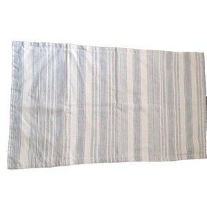 May include: A rectangular, off-white table runner with vertical stripes in varying shades of blue. The fabric appears to be linen or a similar woven material. The stripes are evenly spaced and run the length of the runner.