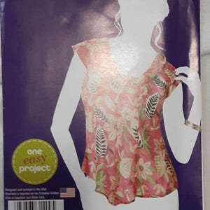 May include: A Simplicity sewing pattern featuring a floral print top. The pattern includes the text "one easy project" and the price "97¢". The design is printed in the USA.