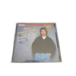 May include: A CD case featuring a man in a black sweater and blue jeans. The CD case has the text "Berlioz Symphonie Fantastique Carnaval romain Orchestre de Paris Semyon Bychkov" and the Philips logo.