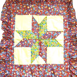 May include: A red and white patchwork quilt with a large star design in the center. The quilt has a ruffled border and is made of floral fabric.