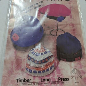 May include: A pattern for making various hats, including a pink beret, a blue cap, and a patterned beanie. The cover reads "Easy Hats" and "Quick Hats for the Whole Family!" The Timber Lane Press logo is visible.