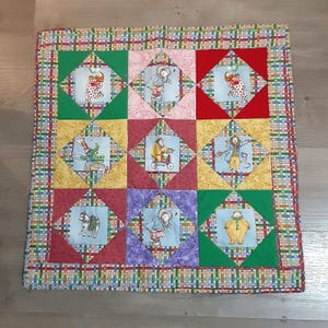 May include: A colorful patchwork quilt with a variety of animal and character designs. The quilt is made of squares with a diamond pattern in each square. The quilt is framed with a green, red, and yellow border.