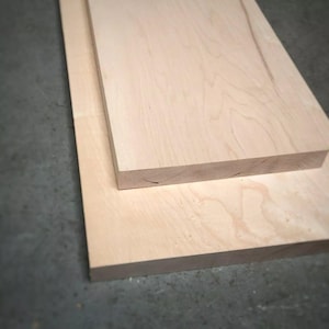 May include: Two unfinished wooden planks, one on top of the other. The wood is a light, natural colour with visible grain patterns. The rectangular planks appear freshly cut, suitable for woodworking projects. The wood is likely to be around 2.5 cm thick.