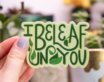 Puede incluir: Una pegatina verde y blanca con el texto "I beleaf in you" con ilustraciones de hojas verdes.