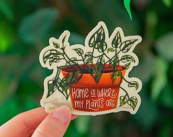 Puede incluir: Una pegatina con una planta en maceta con el texto "Home is where my plants are".
