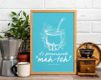 Puede incluir: Una impresión enmarcada con un fondo azul claro que presenta una ilustración blanca de una calabaza mate tradicional sudamericana con una pajita. El texto "it's pronounced "mah-teh"" está escrito debajo de la ilustración.