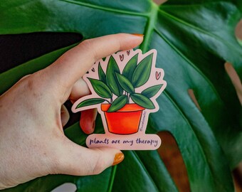 Puede incluir: Una pegatina rosa con una ilustración de dibujos animados de una planta en maceta con hojas verdes y el texto "plants are my therapy".
