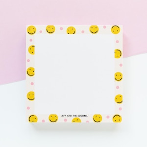 Op de afbeelding: Wit notitieblok met een rand van gele smiley's en roze stippen. Het notitieblok heeft de tekst "JEFF AND THE SQUIRREL" onderaan.
