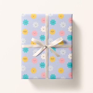 May include: Gift wrapped in light purple paper with a repeating pattern of smiling starbursts in yellow, teal, pink, and white. A white ribbon is tied around the package in a bow.