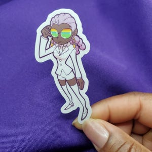 May include: A sticker featuring a cartoon illustration of a person in a white suit, shorts, and shoes, with a lavender hairstyle and rainbow-tinted glasses. The person is wearing gold hoop earrings and is touching their forehead. The sticker is held against a purple background.