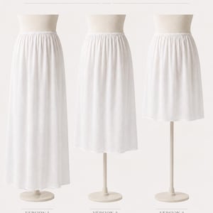 May include: Three white 100% cotton batiste underskirts displayed on mannequins. Version 1 is ankle length, version 2 is midi length, and version 3 is knee length. Each skirt features a simple elastic waistband and a plain, unadorned hemline.