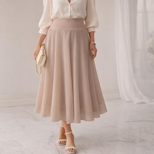 May include: A high-waisted, midi-length skirt in a solid beige color. The skirt features a wide, fitted waistband and a flared, flowing silhouette that falls below the knees. The fabric appears lightweight and semi-sheer with a smooth texture.