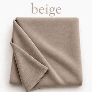 May include: A folded piece of beige fabric with a smooth, solid-colored top surface and a textured, knit-like underside. The word beige is printed in a light brown, sans-serif font above the textile, which is neatly arranged in a square.