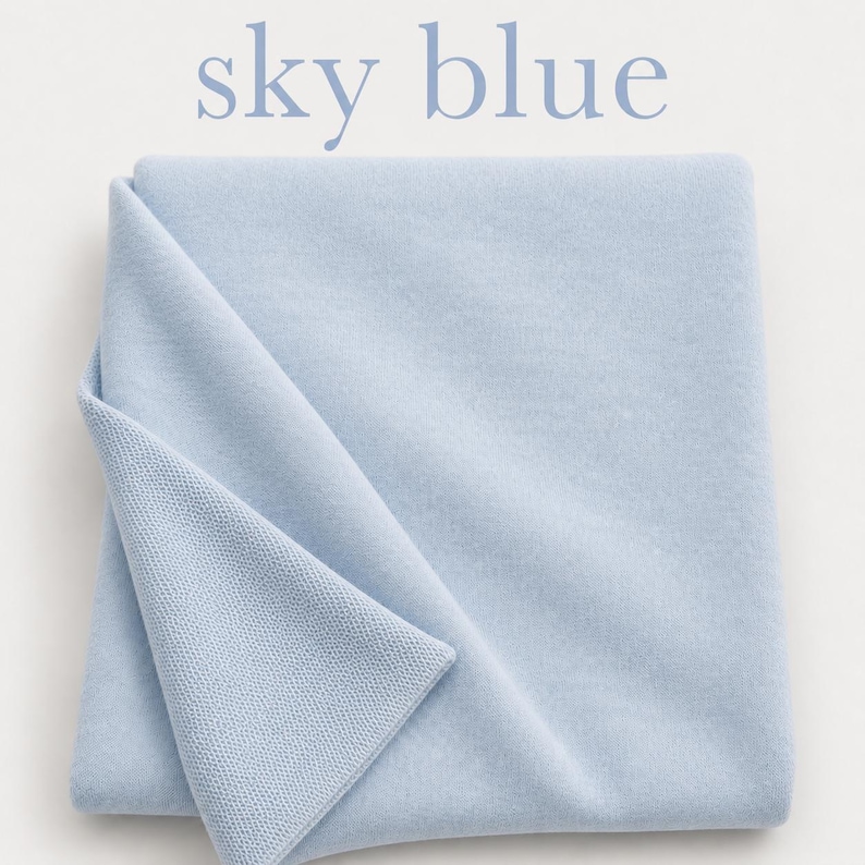 May include: A folded sky blue textile with a smooth surface on one side and a fine knit texture on the other. The text sky blue is printed in light blue letters above the fabric, which is a solid, light, cool-toned blue color.