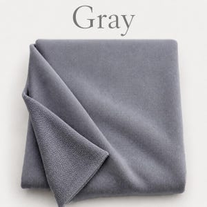 May include: A folded piece of gray fabric with a smooth, matte surface on the top layer and a visible textured, looped knit construction on the underside. The word Gray is printed in a simple serif font above the fabric.