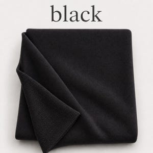 May include: A folded piece of solid black fabric with a visible knit texture. The word black is printed in a serif font above the textile. The fabric is square-shaped and displays a consistent dark tone throughout its surface area.