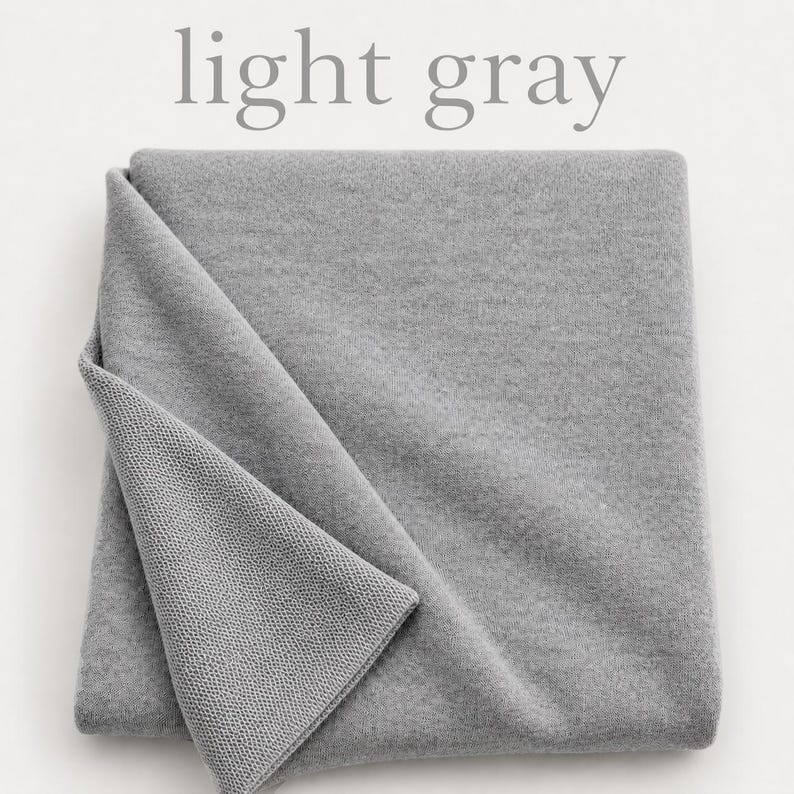 May include: A folded piece of light gray fabric with a smooth, uniform texture on the top layer and a visible knit pattern on the underside. The text light gray is printed in a simple serif font above the fabric.