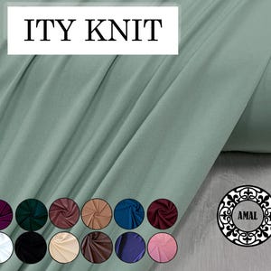 May include: A roll of sage green ITY knit fabric. The fabric is draped, showing its texture and folds. Below the fabric are color swatches in various shades, including burgundy, navy, and pink. The word "AMAL" is in a decorative circle.