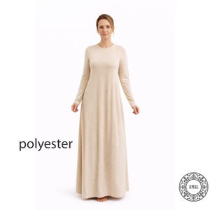 May include: A long, beige, long-sleeved dress made of polyester. The dress has a round neckline and a flowing, floor-length skirt. The word "polyester" is printed in black on the left side of the image. The dress is a neutral color.