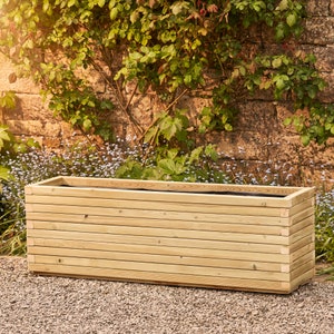 May include: A long, rectangular wooden planter box with a slatted design. The planter is made of natural wood and has a rustic look.