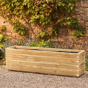 May include: A long, rectangular wooden planter box with a natural wood finish. The planter has a slatted design and is empty.
