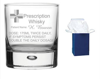 May include: A clear glass whisky tumbler with a white cross and the text "Prescription Whisky" and "Patient Name: H. Bowen" and "DOSE: 175ML TWICE DAILY, IF SYMPTOMS PERSIST DOUBLE THE DAILY DOSAGE". The glass is in a blue gift box with white tissue paper.