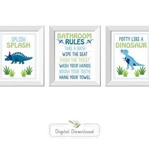 May include: Three framed bathroom art prints with dinosaur themes. One says "Splish Splash" with a blue dinosaur. Another lists "Bathroom Rules." The third says "Potty Like a Dinosaur" with a blue dinosaur.