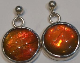May include: A pair of silver dangle earrings with round, orange, iridescent gemstone drops.
