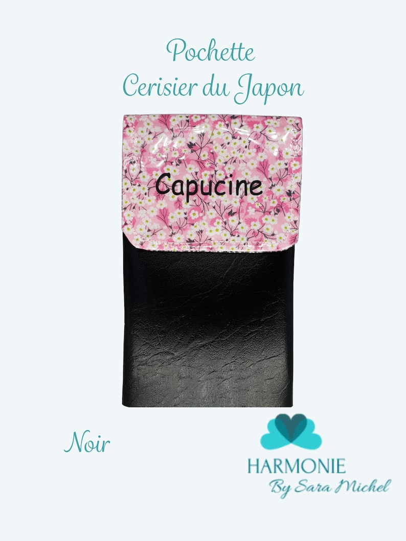 Puede incluir: Cartera negra con solapa con estampado floral rosa y la palabra "Capucine". La cartera tiene el texto "Pochette Cerisier du Japon" y "Harmonie By Sara Michel". Tambi&eacute;n es visible la palabra "Noir".