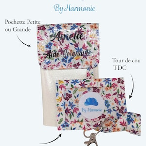 Op de afbeelding: Een lanyard en bijpassende badgehouder met bloemenprint. De lanyard en badgehouder hebben een witte achtergrond met een kleurrijk bloemenpatroon. De badgehouder heeft een zilveren sluiting. De tekst "Amelie Aide Soignante" is zichtbaar.