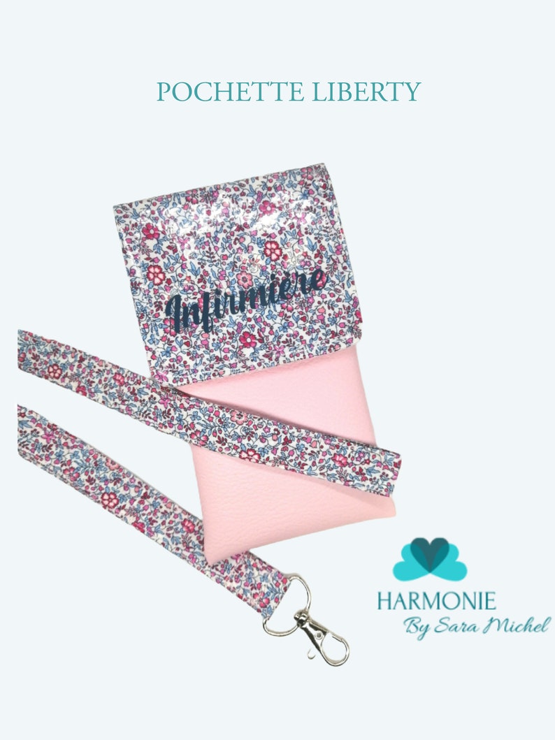 May include: A pink phone case with a floral print and the word "Infirmiere" in blue lettering. The case comes with a matching floral lanyard with a silver clip.