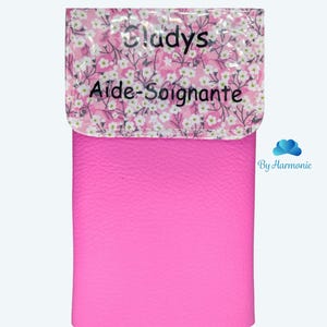 Puede incluir: Un estuche rosa fucsia con una solapa estampada con flores. La solapa tiene el nombre "Gladys" y las palabras "Aide-Soignante" impresas. La parte inferior del estuche tiene las palabras "Fuchsia Barbie" impresas.