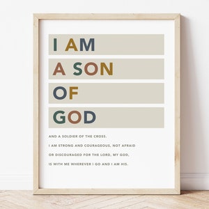 Op de afbeelding: Een beige printbare wandkunstprint met de tekst "I AM A SON OF GOD" in kleurrijke letters. De tekst gaat verder met "AND A SOLDIER OF THE CROSS. I AM STRONG AND COURAGEOUS, NOT AFRAID OR DISCOURAGED FOR THE LORD, MY GOD, IS WITH ME WHEREVER I GO AND I AM HIS."