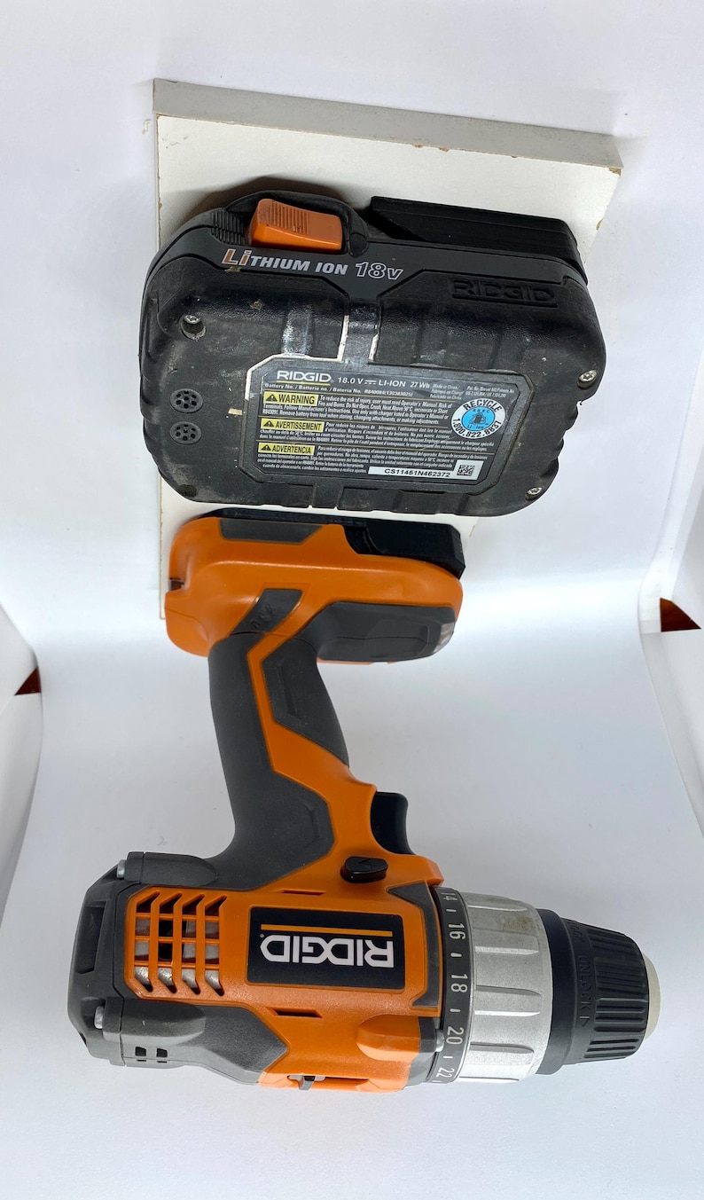 K&ouml;nnte beinhalten: Ein schwarzer und orangefarbener Ridgid-Bohrer mit einem 18-V-Lithium-Ionen-Akku. Der Bohrer hat eine Kupplungseinstellung von 1 bis 22. Der Akku tr&auml;gt den Text "RIDGID 18.0V LI-ION 2.71Ah".